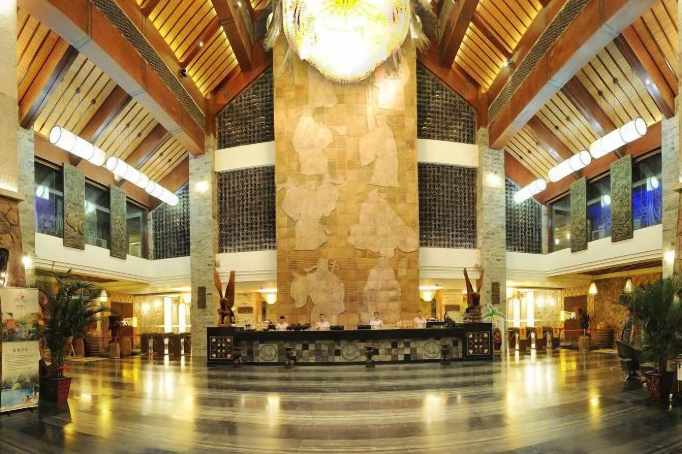 A spacious lobby with a high ceiling, a central reception desk, and a large decorative wall.