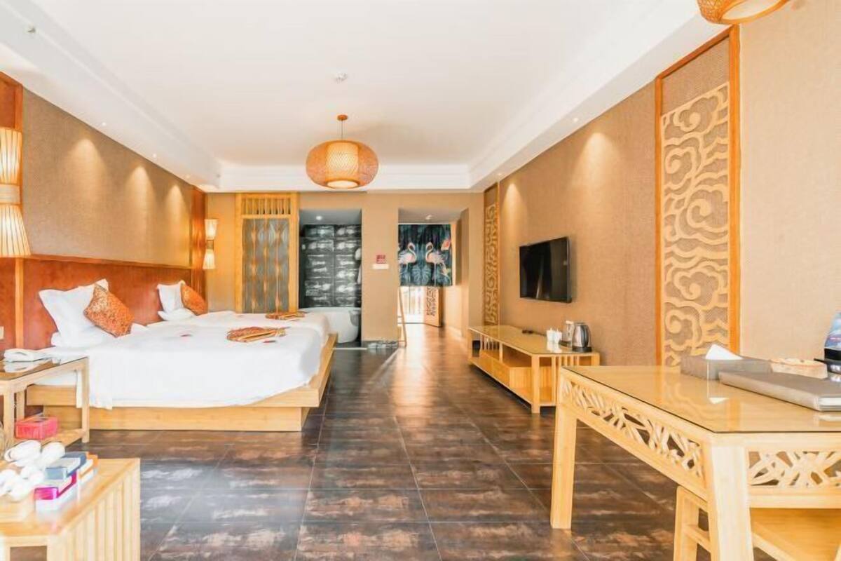 A hotel room with a bed, bedside table, TV, and a view of the cityscape.