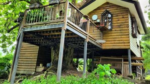 A treehouse with a wooden exterior, a balcony, and a small window.