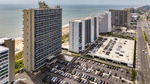 Un hotel moderno de muchas plantas, con estacionamiento y vistas a la playa y al océano.