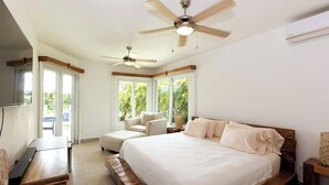 Ein Schlafzimmer mit einem großen Bett, zwei Deckenventilatoren, einer Couch und einem Fernseher.