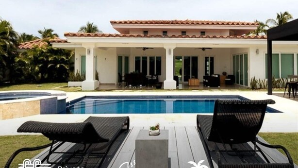 Eine private Villa mit Swimmingpool, Sitzgelegenheiten im Freien und einer überdachten Terrasse.