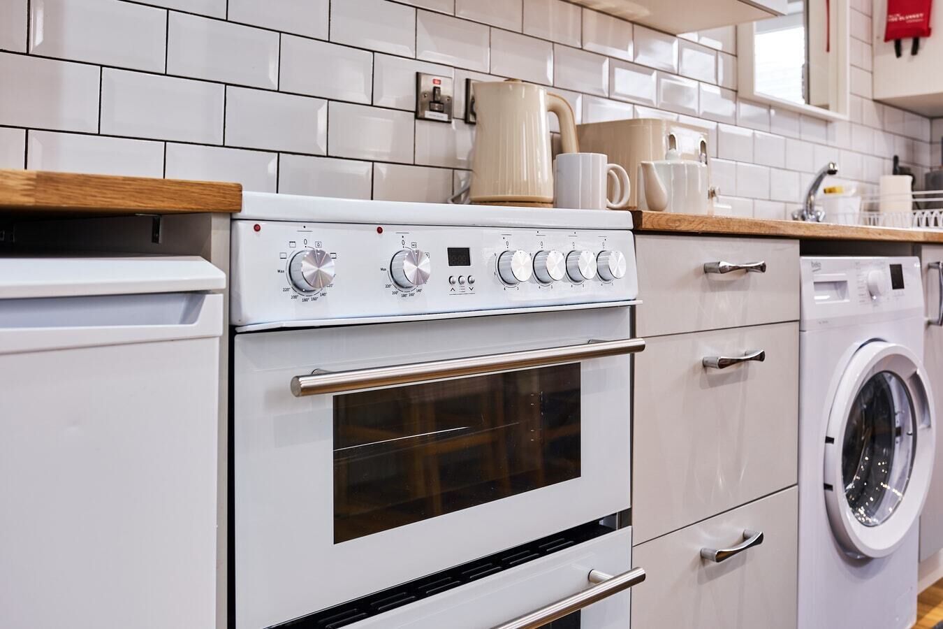 A kitchen with a white stove, oven, and washing machine.