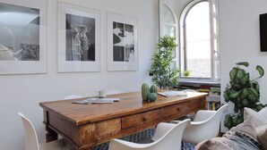 A dining area with a wooden table, white chairs, and framed artwork on the wall. - Designer Duplex 2BR 2BA by Colosseum - Historic Center, Metro (Roma)
