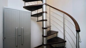 A spiral staircase with metal railings and wooden handrails, leading to an upper floor. - Designer Duplex 2BR 2BA by Colosseum - Historic Center, Metro (Roma)