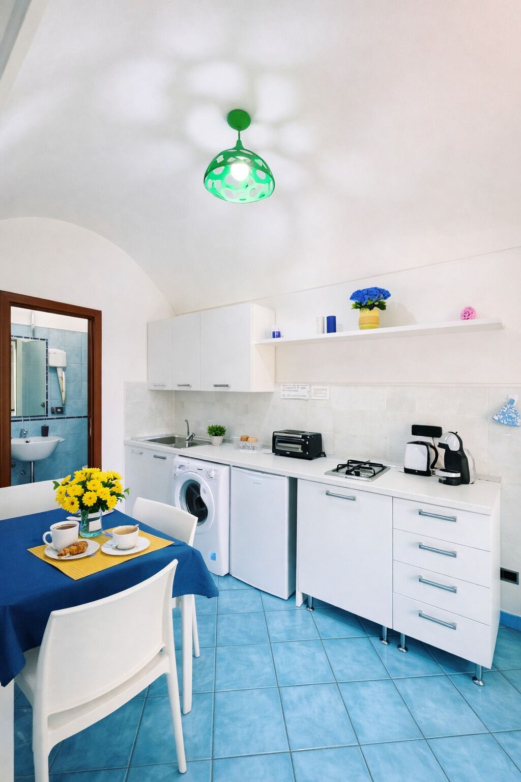 Eine kleine Küche mit Waschmaschine, Toaster und Kaffeemaschine.