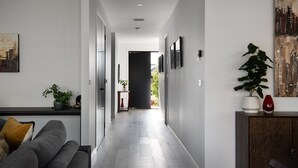 Ein moderner Flur mit einem grauen Sofa, einem Topf mit Pflanze und einem Schrank.