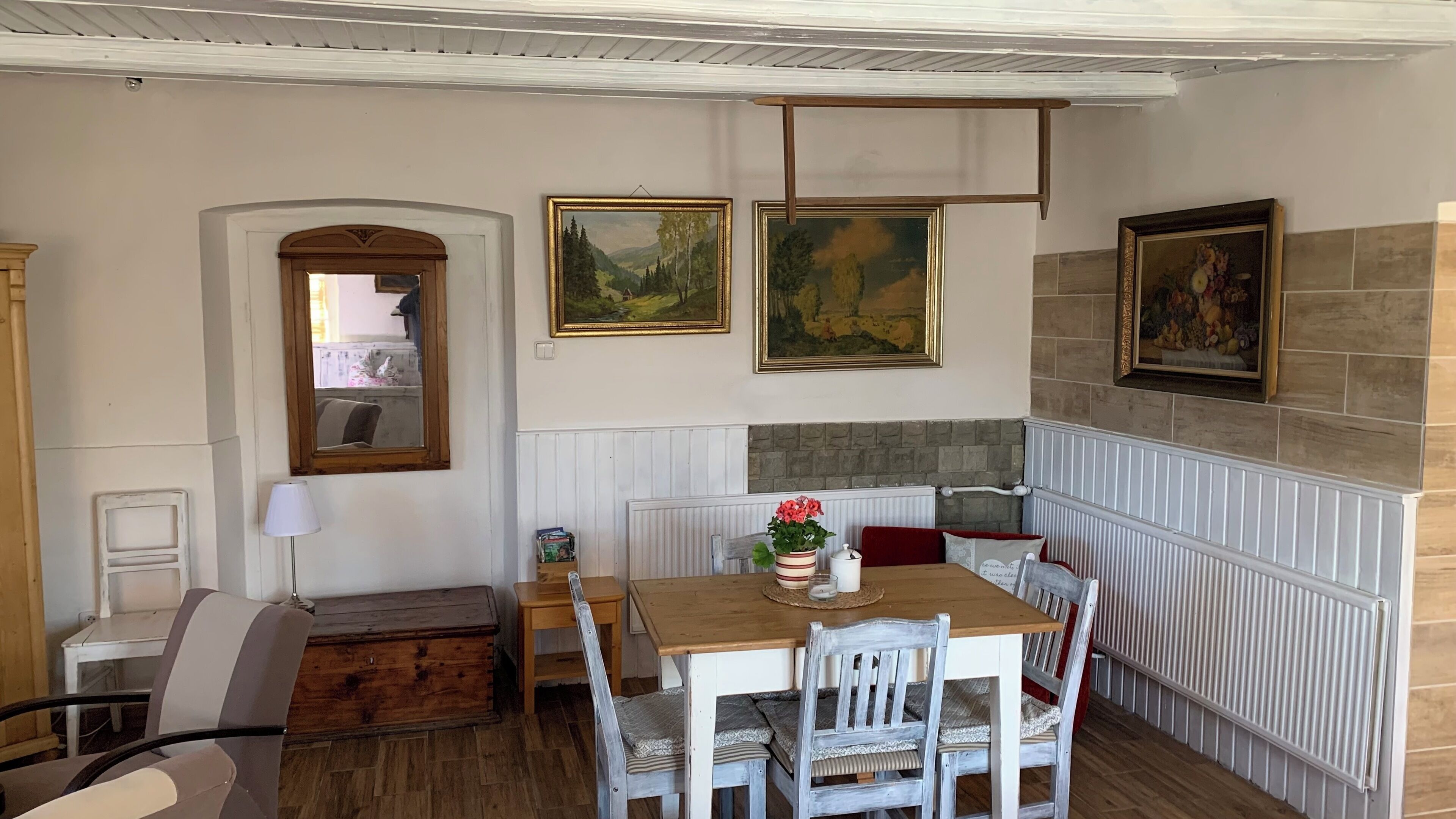A dining area with a wooden table, white chairs, a bench, and a fireplace.