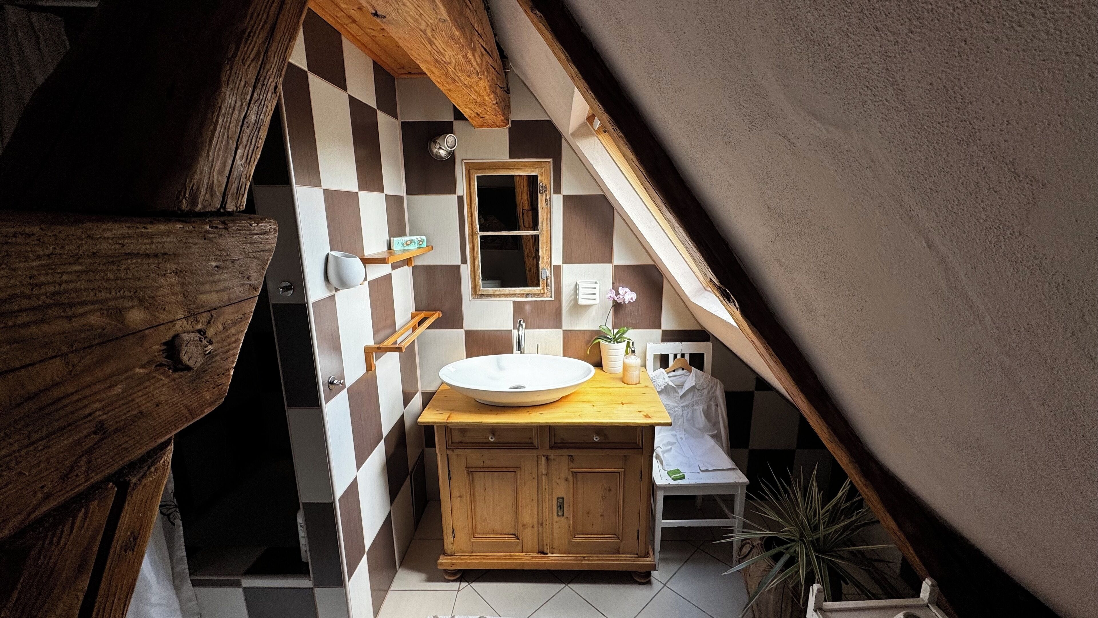 A bathroom with a checkered tile wall, wooden cabinets, a white sink, and a mirror.