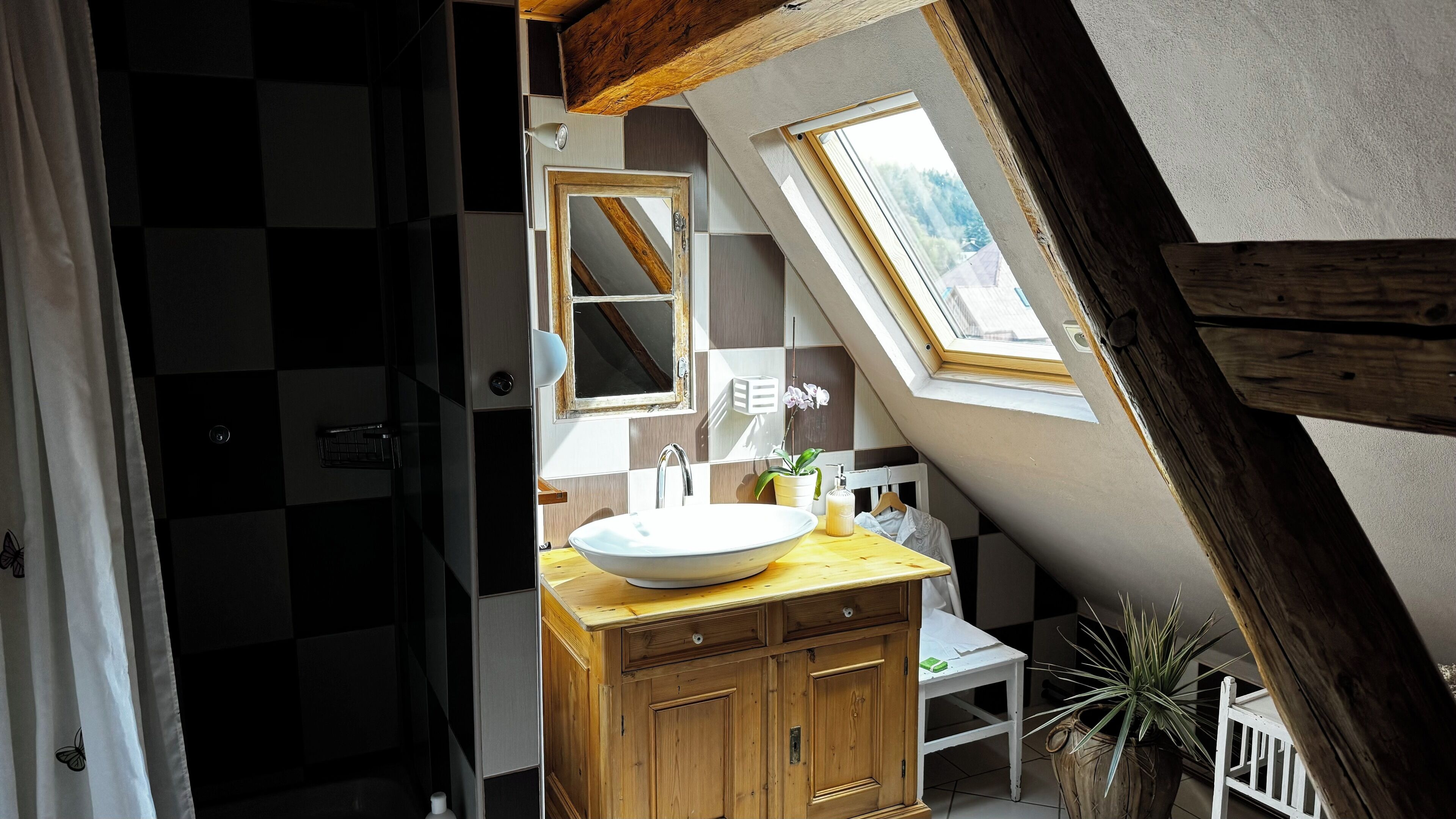 A bathroom with a skylight, a white sink, wooden cabinets, and a mirror.