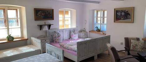 A bedroom with a wooden bed, a nightstand, a dresser, and a window with a plant.