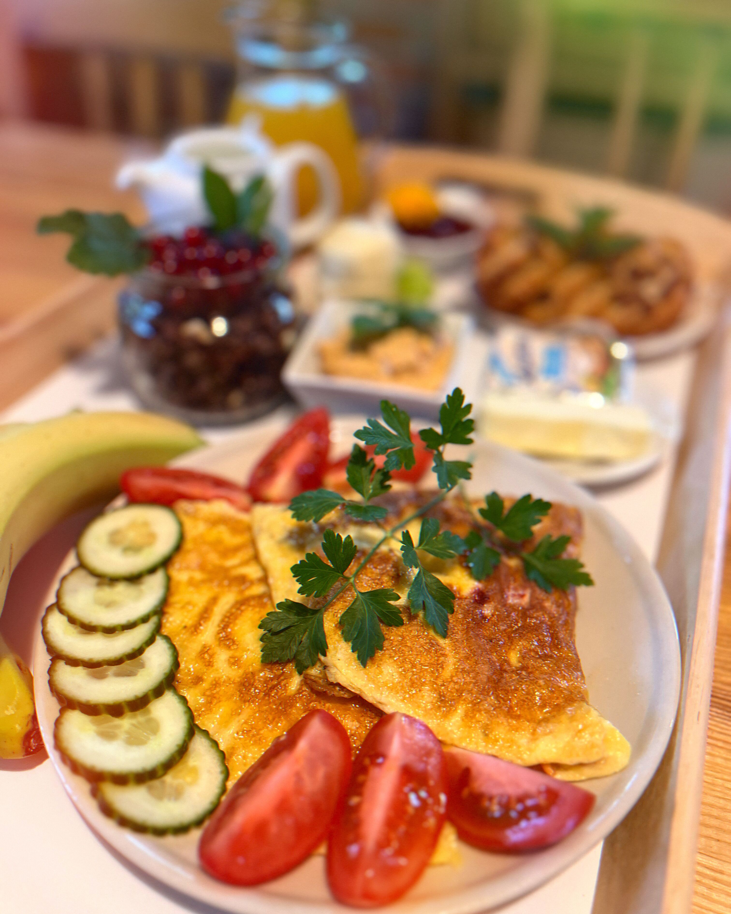 Bandeja de desayuno con una tortilla, tomates, pepinos y perejil.