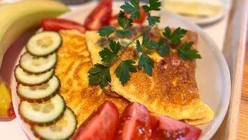 Bandeja de desayuno con una tortilla, tomates, pepinos y perejil.