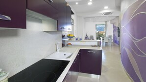 A modern kitchen with a central island, built-in appliances, and a view into the dining area. - Estate4home- L'Onda Viola (Sorrento)
