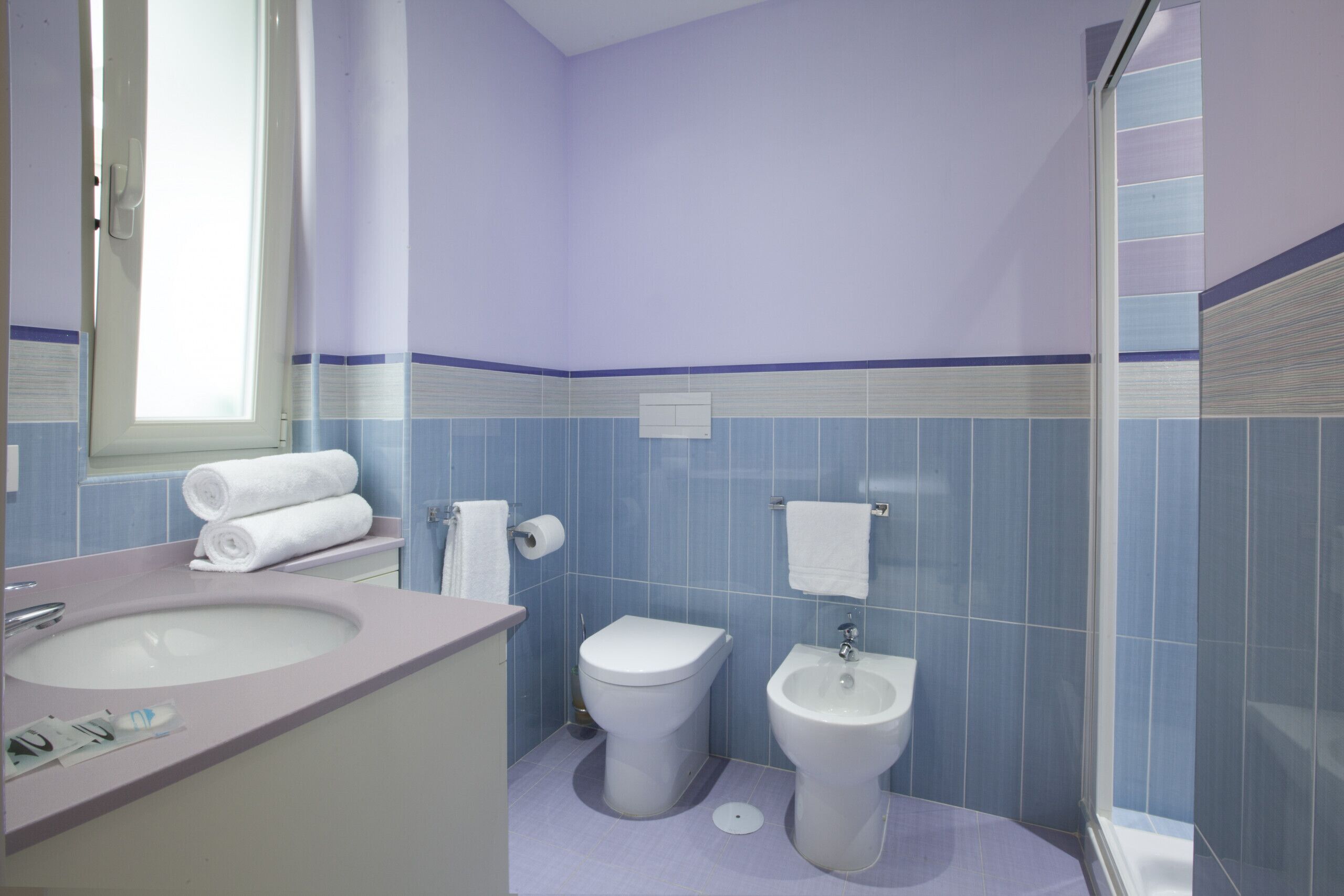 Un baño con lavamanos, inodoro, bidé y cabina de ducha de vidrio.