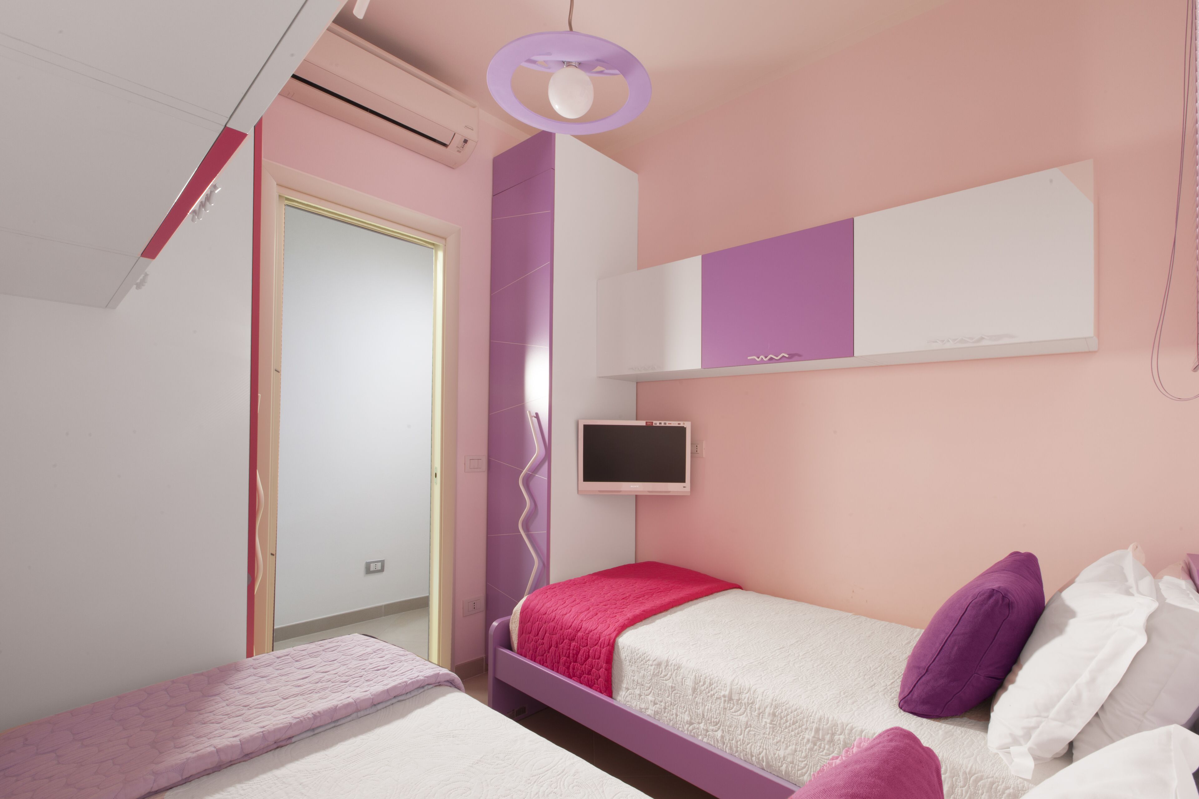 Une chambre à coucher avec un lit, une télévision et une porte.