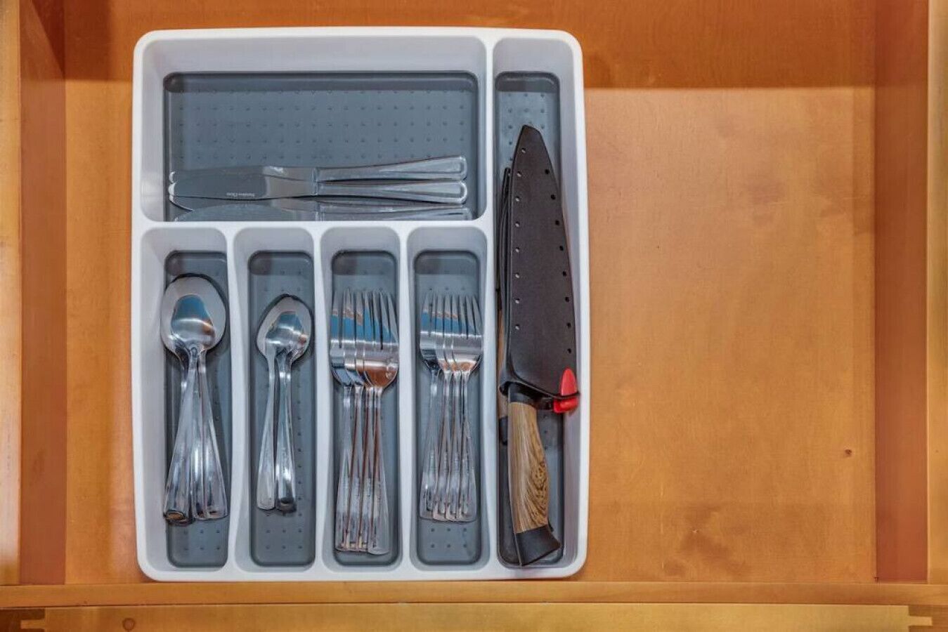 Un cajón con un cuchillo, tenedores, cucharas y un juego de palillos.