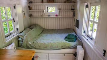 Een gezellige kamer met een bed, een klein tafeltje en een raam met uitzicht op groen.