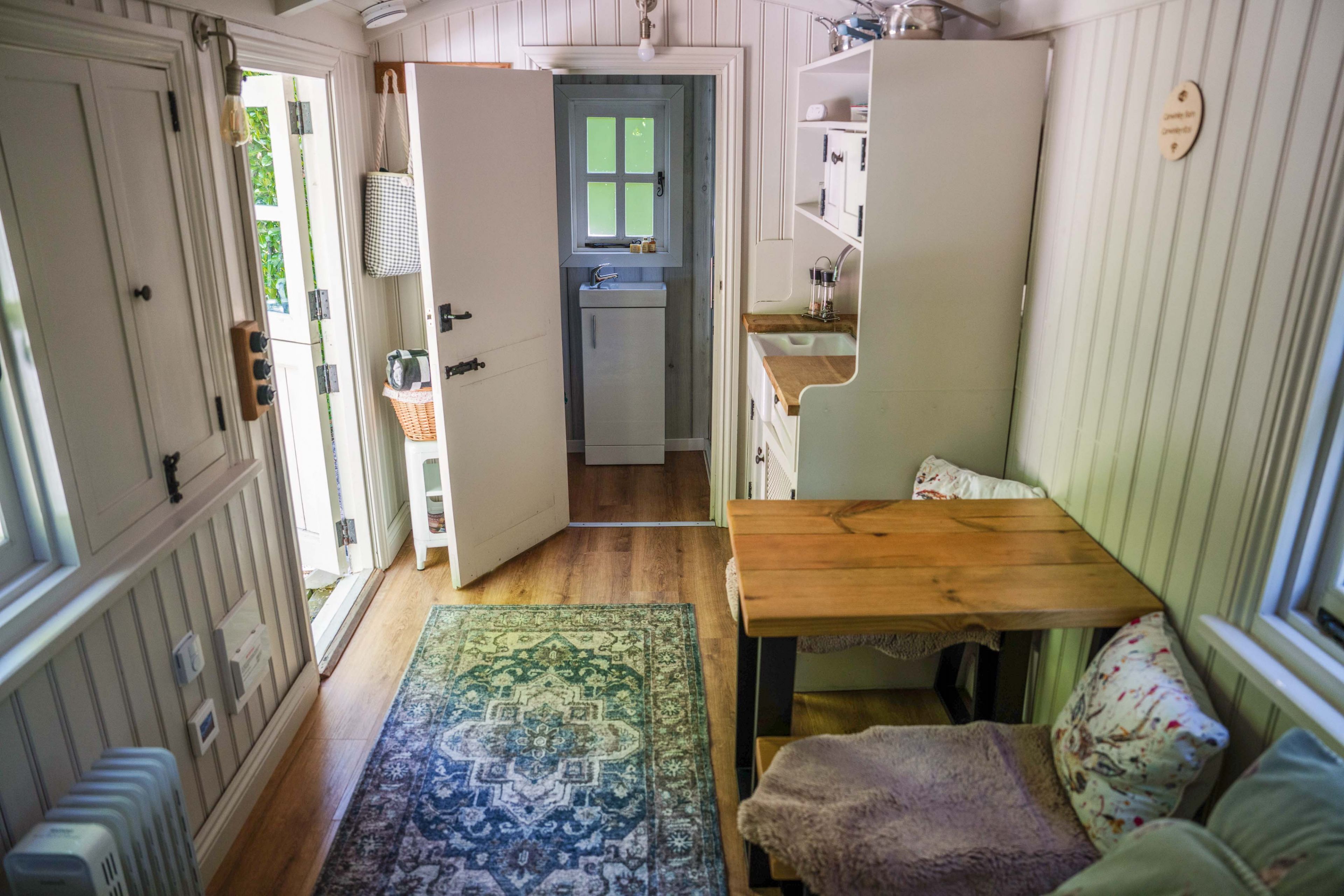 Een kleine keuken met een spoelbak, een klein raam en een houten tafel.