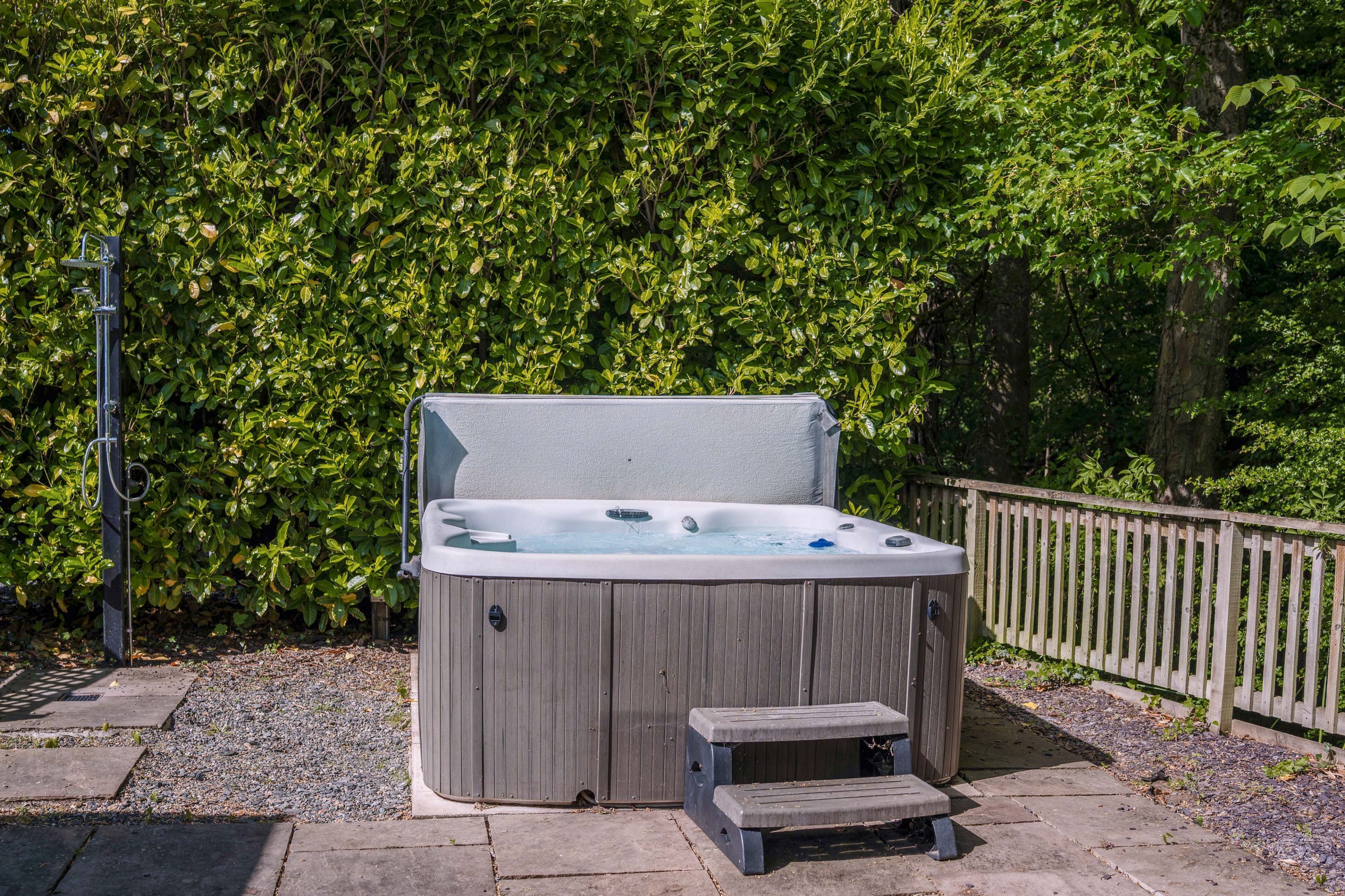 Un jacuzzi en un entorno al aire libre con una terraza de madera y un cerco de madera.