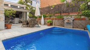 Um quintal com piscina, móveis de exterior e plantas em vasos.