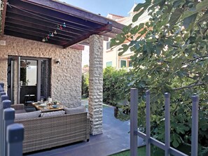 A patio with a stone wall, wicker furniture, and a pergola.