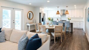 A modern kitchen with white cabinets, a dining area with a round table and chairs, and a large window providing natural light. - Private Pool + STEPS to Beach! LSV/Golf Cart, Bikes, Pet Friendly! Coastal Charmer! (Santa Rosa Beach)