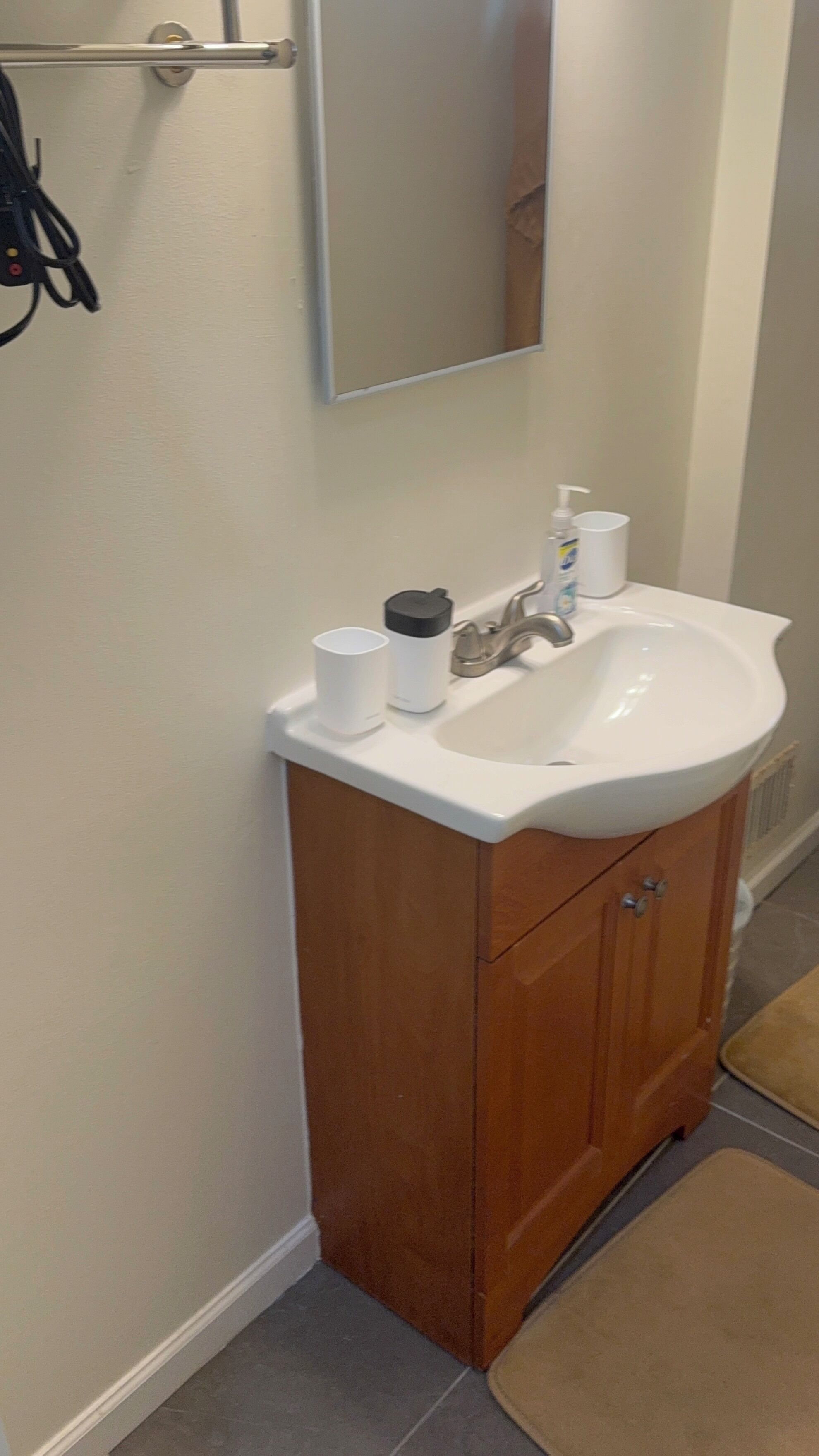 Un baño con lavamanos blanco, un espejo y un mueble de madera.