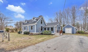 Une maison à deux étages avec un porche à l’avant, un garage et une pelouse bien entretenue.