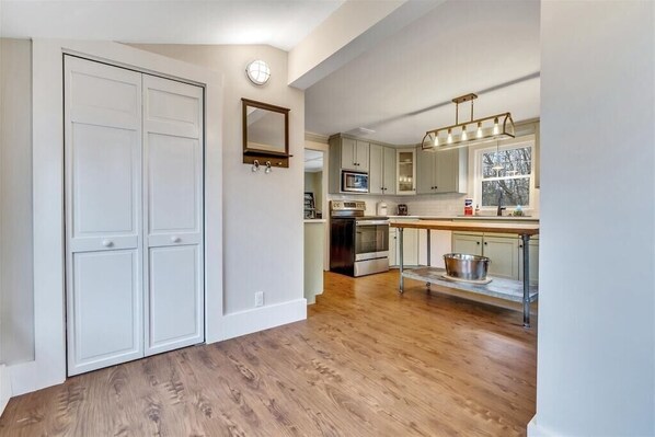 A kitchen with wooden flooring, white cabinets, a microwave, and a sink. - Steps to Dock Square & Gooch's Beach! Pets Welcome! (Kennebunk)