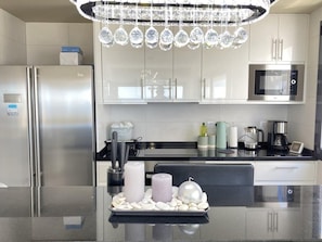 Een moderne keuken met roestvrijstalen apparatuur, een centraal eiland met decoratieve stenen en een kroonluchter erboven.