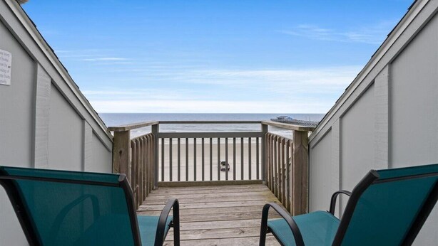 A wooden deck with two green chairs facing a beach. - Condo w/ Private Balcony & Stunning Views | Family Friendly (Garden City Beach)