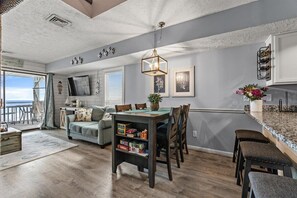 Enjoy a spacious living area with a dining space, large window, and bookshelf, perfect for relaxation and reading.
