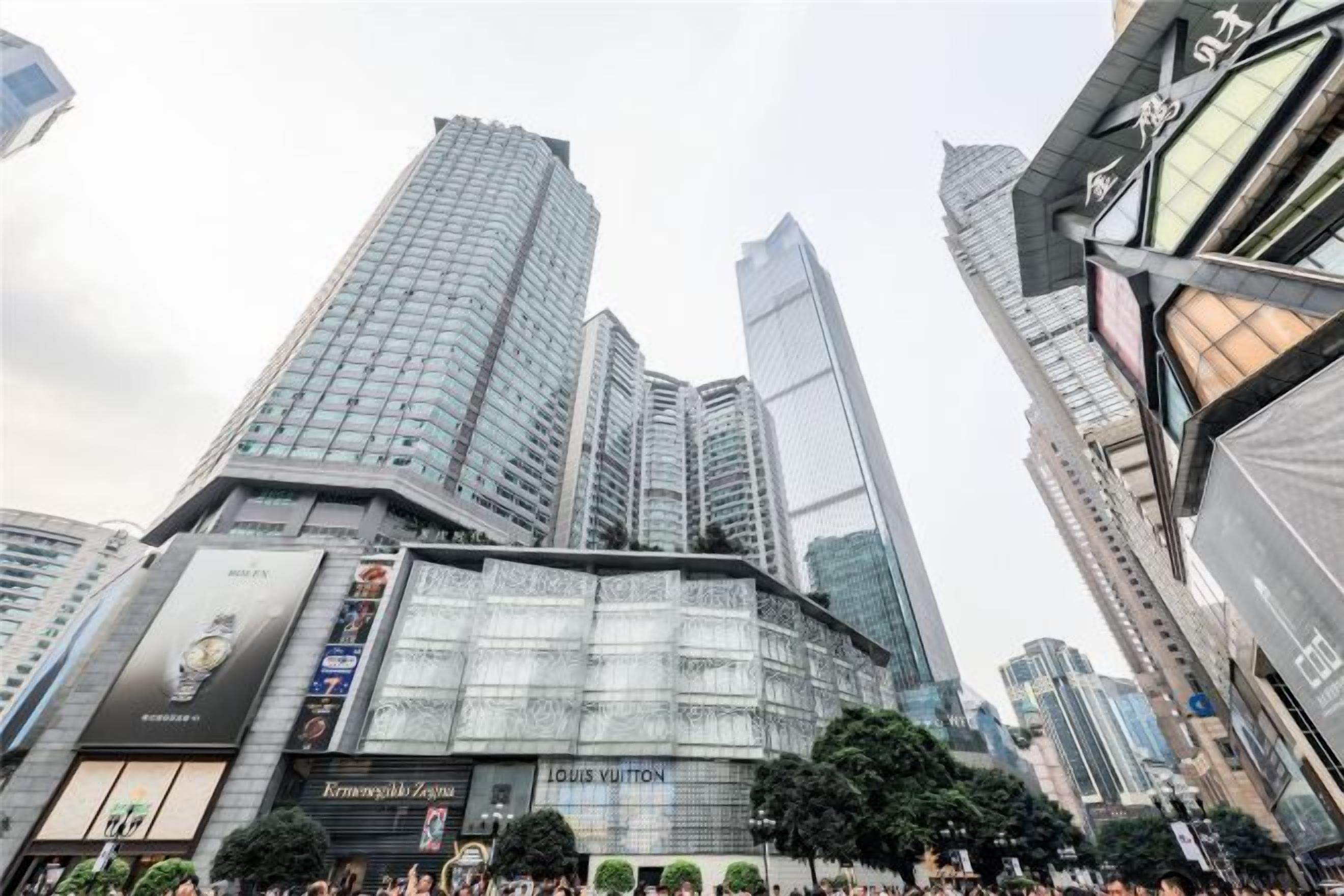 Un edificio de gran altura con una fachada de vidrio destacada y una tienda Louis Vuitton en la planta baja.