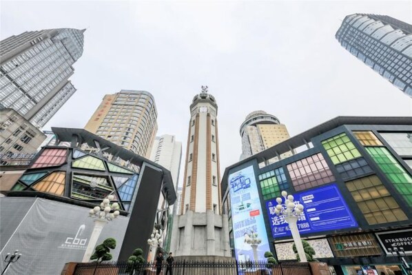 A cityscape with modern high-rise buildings, a prominent tower, and a large digital advertisement board. - Qidian Esports Hotel (Chongqing)