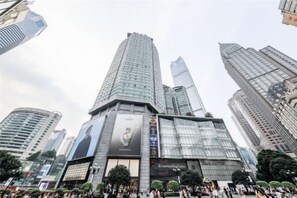 Un edificio de gran altura con varios pisos, amplias ventanas de vidrio y un anuncio llamativo en la fachada.