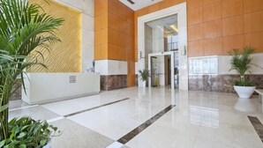 A reception area with a reception desk, potted plants, and a large wall with a textured design.