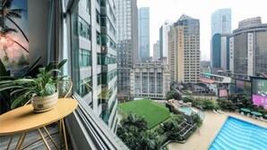 A high-rise building with a view of a cityscape, a small outdoor pool, and a potted plant on a balcony.