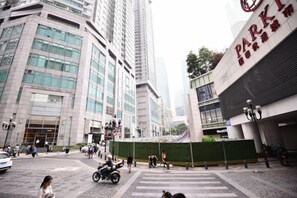 Una calle urbana concurrida, con edificios altos, un paso de peatones y una obra en construcción.