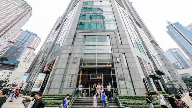 A modern high-rise building with a glass facade, multiple floors, and a central entrance with steps.