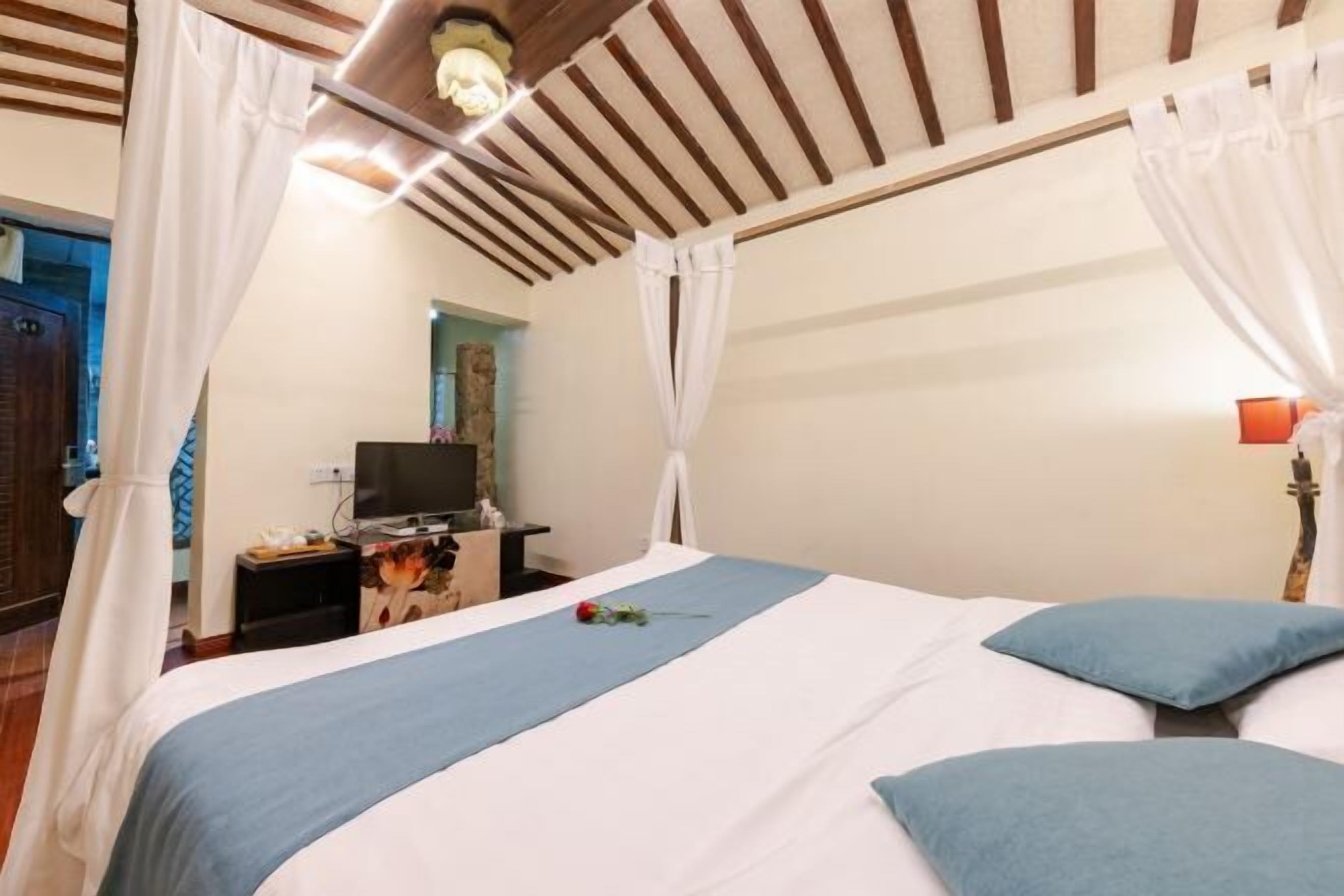 Un dormitorio con cama, cortinas, televisor y mesita de noche.