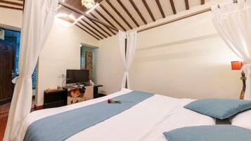 Un dormitorio con cama, cortinas, televisor y mesita de noche.