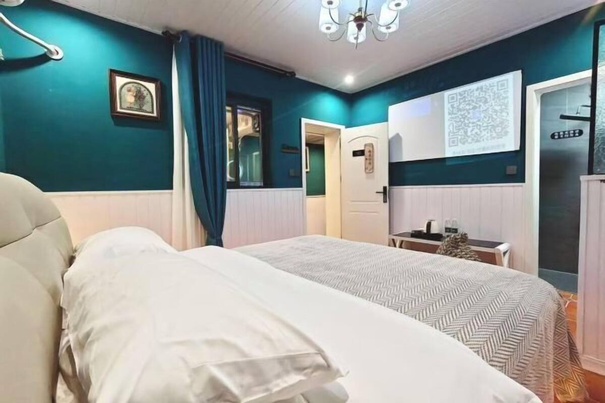 Une chambre avec deux lits, un bureau, une chaise, une fenêtre avec des rideaux, une porte et un lustre.