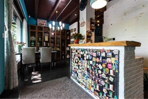Un intérieur chaleureux avec un comptoir d’accueil en bois, un mur décoré de photos et un espace détente avec des fauteuils.