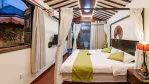 Ein Schlafzimmer mit Bett, Vorhängen, einem Nachttisch und einem Beistelltisch.