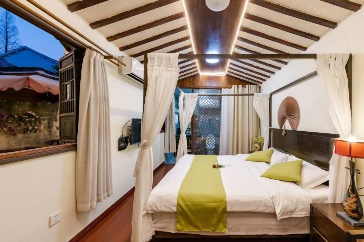 Une chambre à coucher avec un lit, des rideaux, une table de chevet et une commode.