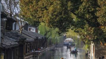 A narrow waterway flanked by traditional buildings with wooden roofs and a person in a boat.
