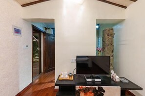 Een moderne woonkamer met een flatscreen-tv op een zwarte standaard, een klein tafeltje met decoratieve voorwerpen, en een accentmuur van steen.