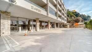 A modern hotel with a stone facade, numbered 24980, featuring a spacious outdoor area with a covered seating area and a clear view of the surrounding landscape. - Miramar Deluxe con Vista al Mar (Concón)