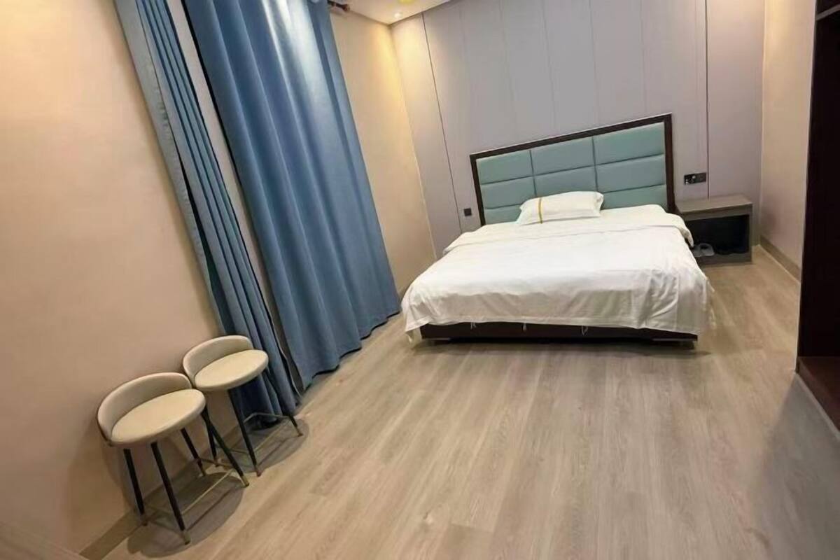 A modern hotel room with a bed, a nightstand, and two chairs.